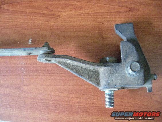 Metal transfer case component with a threaded bolt and a lever arm, on a wooden surface