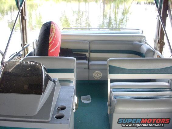 Pontoon boat interior with gray and teal striped seats, a helm, and a tube