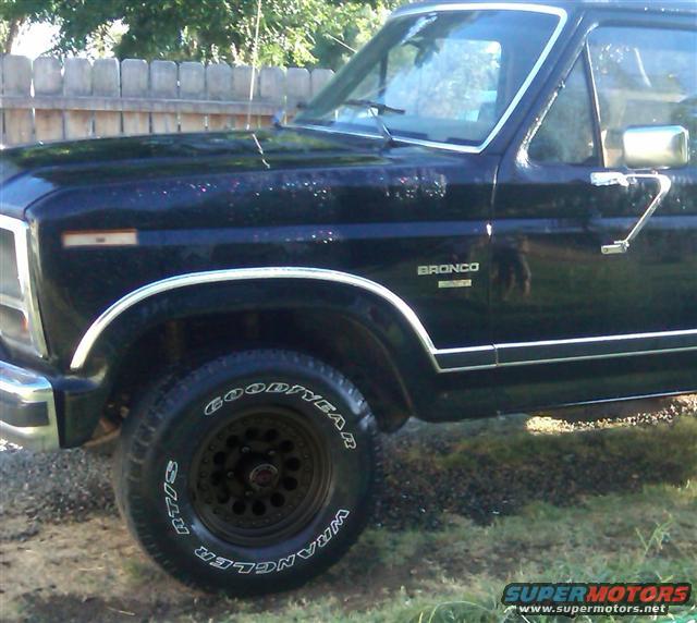Black Ford Bronco, front fender and door visible, chrome trim, Goodyear Wrangler tires