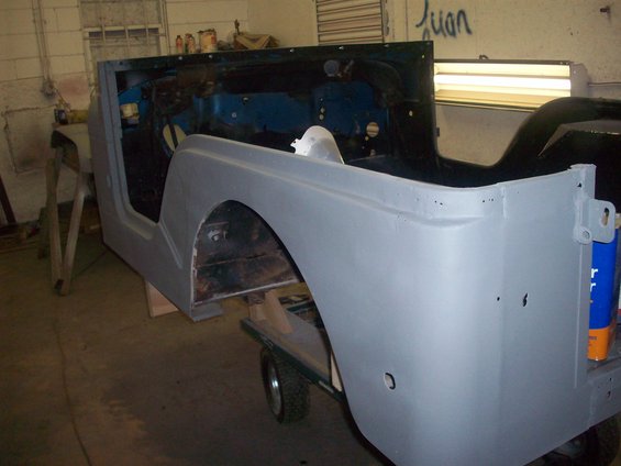Gray Jeep CJ-5 body in primer, side view, undergoing restoration
