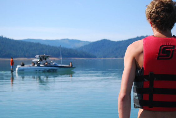 Boat on a lake with people, viewed from behind a person in a life vest