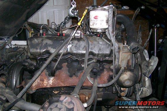 Engine with oil filter and fan assembly, being lifted by a chain hoist