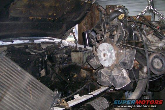 engine hoisted by chains, with radiator and part of vehicle interior visible