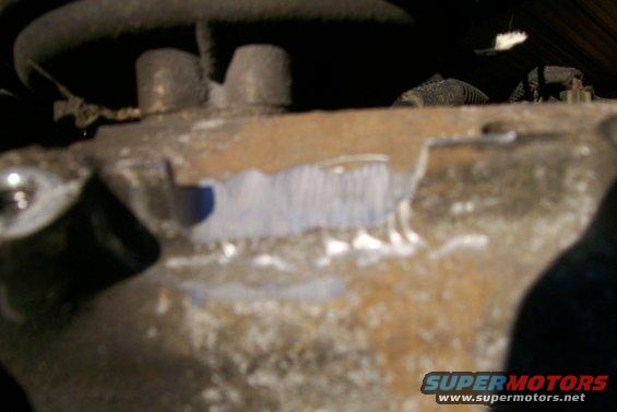 Close-up of a rusty metal engine component with some blue and white markings