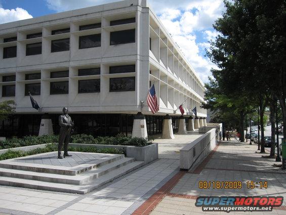 Building with a statue in front and American flags, on a sunny day