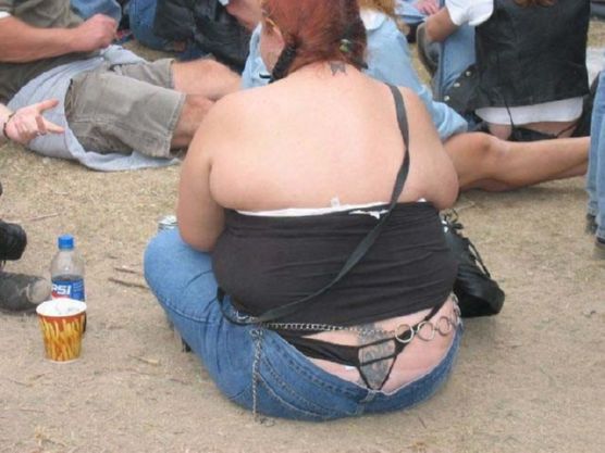 People sitting on the ground, one person in the foreground wearing jeans and a black top