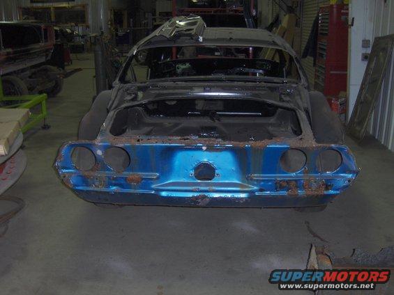 Blue 1970 Chevrolet Camaro body in a workshop, showing rust and missing parts