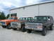 1975 Ford F-250 - Three Ford trucks, including a black 1975 F-250 with a camper shell, are lined up outside a building.