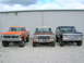 1975 Ford F-250 - Three Ford trucks from the 1970s are parked in front of a building.