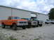 1975 Ford F-250 - Several Ford trucks and Broncos are lined up in front of a metal building on a cloudy day.