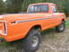 1975 Ford F-250 - This lifted pickup truck is shown from the rear quarter, with a focus on its large off-road tires and bright orange paint.