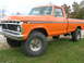 1975 Ford F-250 - This orange 1975 Ford F-250 pickup truck is shown from a 3/4 front angle, highlighting its grille and overall body style.