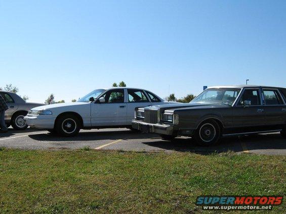 White sedan and a dark sedan parked next to each other