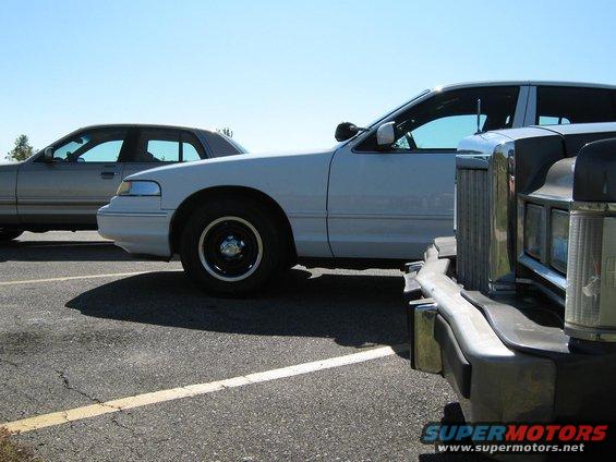White sedan parked next to a silver sedan, with a dark vehicle in the foreground