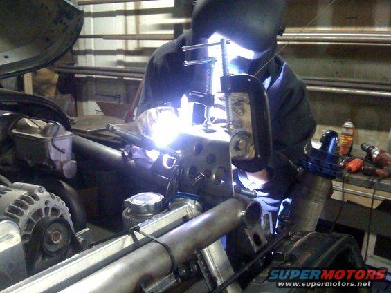 Welder working on engine bay with bright sparks
