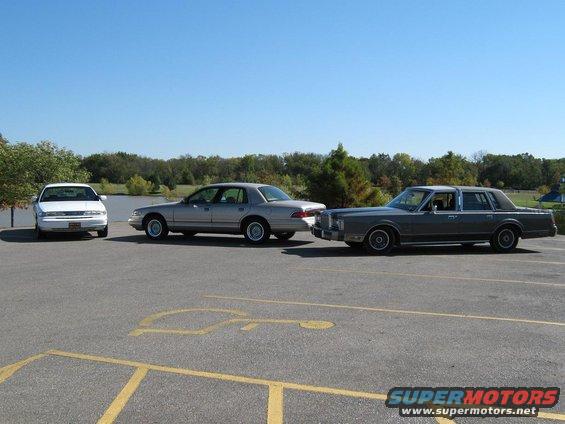 Three sedans parked side-by-side, a white sedan, a silver sedan, and a dark gray sedan