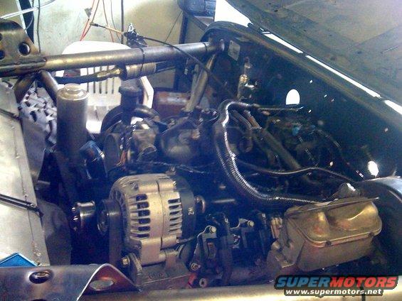 Engine bay showing alternator, hoses, and engine components