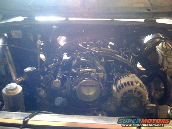 Engine bay with V8 engine, alternator, and intake manifold visible