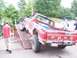 1989 Ford F-150 - A red Ford pickup truck is being driven up a ramp, with people watching in the background.