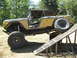 1973 Ford Bronco - Modified 1973 Ford Bronco with off-road tires is positioned on a metal ramp.