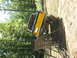 1973 Ford Bronco - A yellow off-road vehicle is positioned on a metal ramp, with trees and dirt surrounding it.
