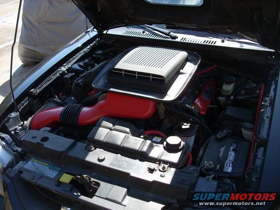 Engine bay with red intake tubing and a large black air intake scoop
