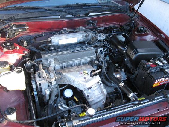 Red 1994 Toyota Camry engine bay with 4-cylinder engine, battery, and radiator visible