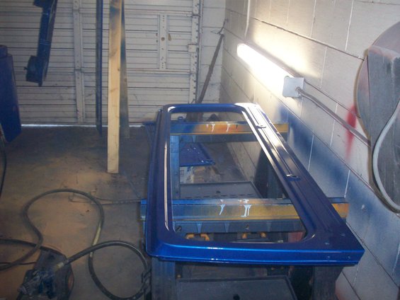 Blue hardtop frame on a stand, possibly being painted
