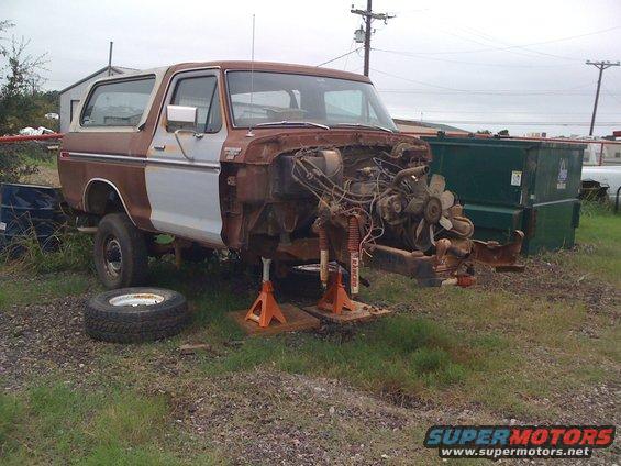 Rusty 1978 Ford Bronco with front end removed, sitting on jack stands. Spare tire is on the ground