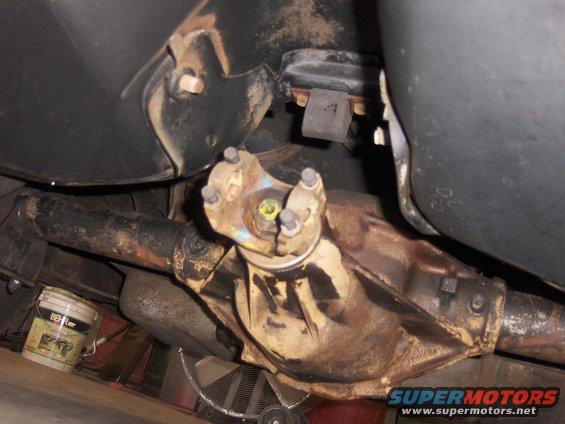 Underside view of a rusty rear differential and driveshaft assembly