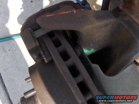 Close-up of a rusty vehicle brake rotor and caliper assembly