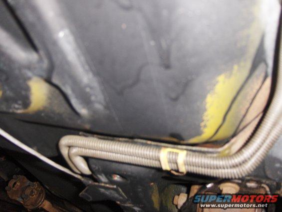 Underside of a vehicle with a corrugated tube secured by a yellow clip