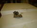 2005 Ford Excursion - A rusty metal bracket is shown on a white surface, possibly a hood or tailgate.