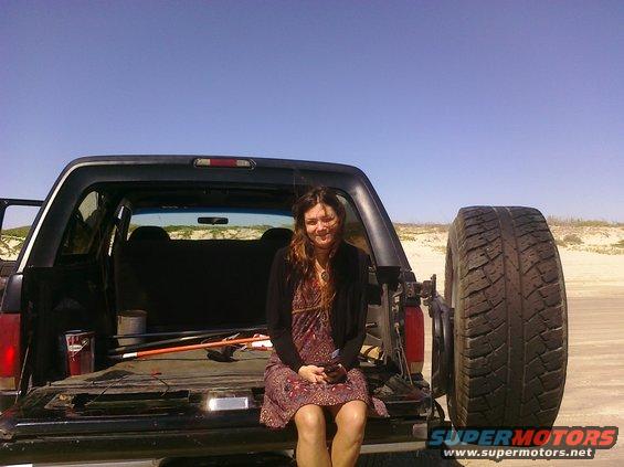 Woman sitting in the open tailgate of a 1993 Ford Bronco, spare tire mounted on the rear