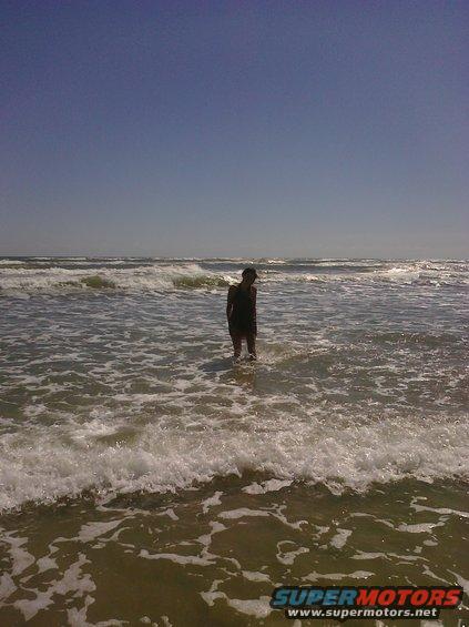 Person standing in ocean waves with whitecaps