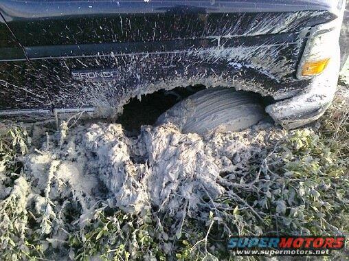 1993 Ford Bronco stuck in mud, front passenger side wheel deep in muck
