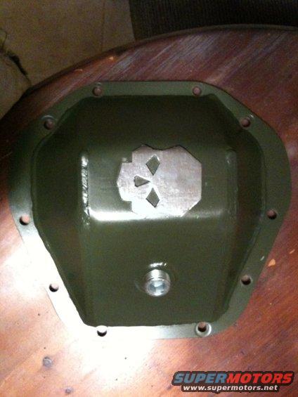 Green differential cover with a metal plate cut into a skull shape inside. Has a threaded plug at the bottom