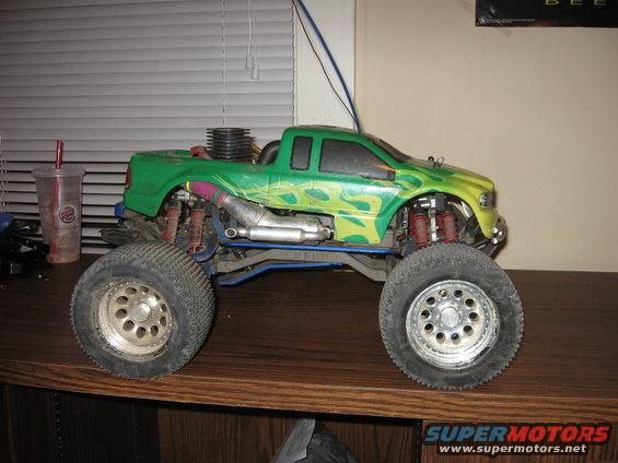 Green remote control monster truck with flame decals, large tires, and visible engine components