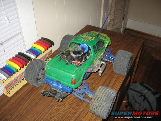 Green remote control monster truck with exposed engine and colorful shock absorbers on a wooden table