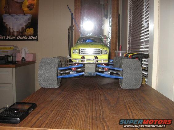 Yellow remote control monster truck with large tires and blue suspension, front view
