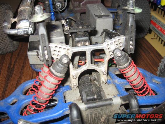RC car chassis with red coilover shocks, silver suspension arms, and blue plastic frame