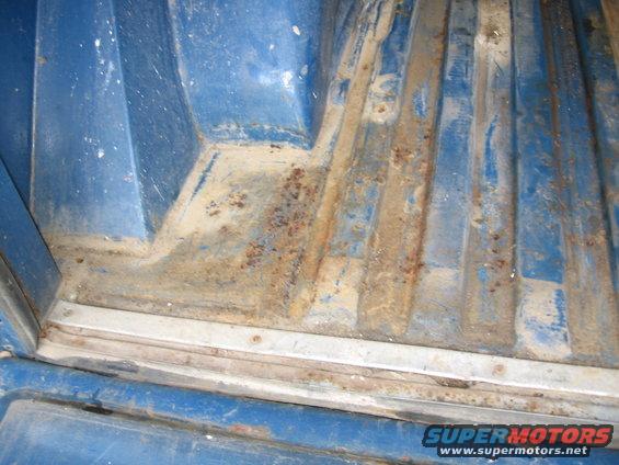 Blue truck bed with ribbed floor showing rust and dirt