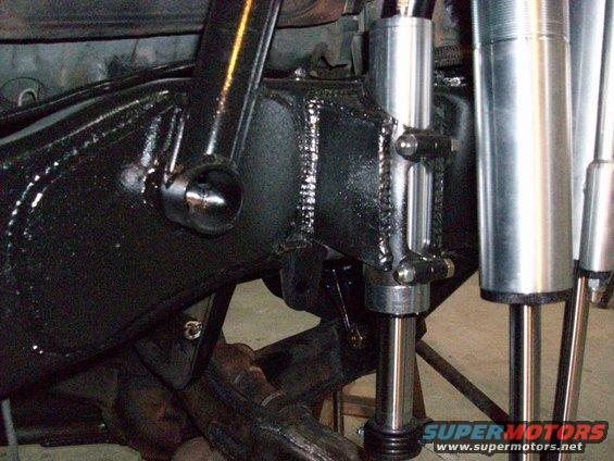 Close-up of aftermarket off-road suspension components, including shocks and fabricated brackets