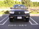 2000 Toyota 4Runner - This black Toyota 4Runner is parked in a lot with trees in the background.