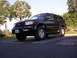 2000 Toyota 4Runner - This black 2000 Toyota 4Runner is parked in a lot with trees in the background.