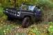1988 Chevrolet Blazer - A person navigates a black SUV through a wooded trail during autumn, with mud and fallen leaves on the ground.