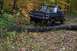 1988 Chevrolet Blazer - A black SUV navigates a fallen tree on a wooded trail during autumn.