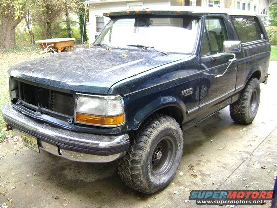 Dark blue Ford Bronco, lifted with off-road tires, parked in a driveway