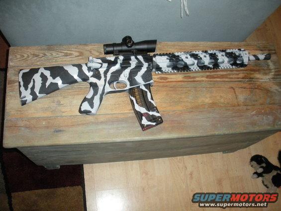 Rifle with black and white camouflage paint and a scope