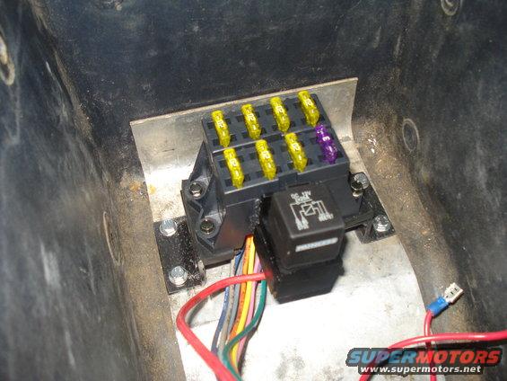 Fuse box with yellow and purple fuses, and a black relay